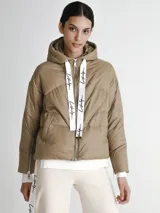 Campera puffer color visón con capucha y cierre frontal con cremallera. Presenta cordones blancos con letras negras en la capucha y en los puños.