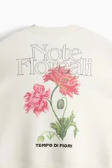 Buzo de corte holgado color blanco con cuello redondo acanalado, hombros caídos y diseño estampado en el pecho con la frase 'Note Floreat'. Cuenta con puños y bajo acanalados anchos.