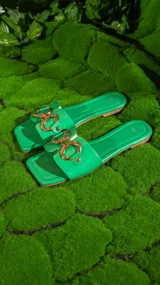 Sandalias negras con base cuadrada y tira ancha sobre el empeine, con aplique de cadena dorada.