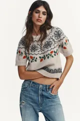 Jersey de punto de cuello redondo y manga corta, color beige con diseño de jacquard geométrico y bordados de flores y hojas en tonos rojos y verdes.