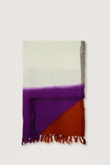 Bufanda tipo manta suave con diseño en bloques de color blanco, violeta y naranja, con flecos en los extremos.