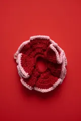 Colita de pelo tejida a crochet con diseño de volados, combinando los colores rojo y rosado.