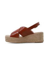 Sandalia de plataforma con yute trenzado, tiras cruzadas de cuero marrón arrugado y tira ajustable al talón con hebilla metálica.