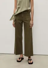 Pantalón de jean color verde oliva, de corte wide leg, tiro alto y largo al tobillo. Tiene bolsillos de parche delanteros y traseros, trabillas para cinturón y cierre frontal con cremallera y botón.