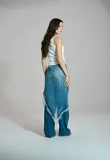 Musculosa blanca de líneas sencillas, con escote cuadrado y tirantes finos que presentan un detalle de ancla dorada en uno de ellos.