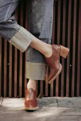 Zapato de cuero color beige, con taco de madera y suela dentada. Presenta un diseño slip-on con detalles de textura en relieve en los laterales y el empeine.