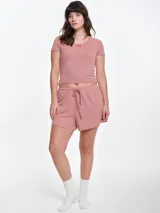 Remera de manga corta entallada en tejido pointelle, con escote redondo y detalle de picot con lazo pequeño en el centro. Diseño ajustado al cuerpo con textura acanalada.