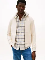 Buzo con cierre de cremallera, confeccionado en felpa de algodón color crema. Cuenta con cuello chimenea, dos bolsillos delanteros tipo canguro, puños y bajo de punto canalé. Incluye logo de Tommy Hilfiger bordado en el pecho.