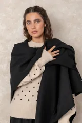 Ruana abierta de color beige, confeccionada en tejido de punto con terminación de flecos en el ruedo.