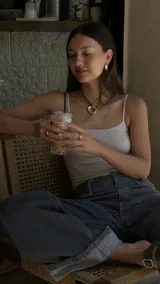 Collar con dije de forma irregular en tonos dorados y plateados, suspendido de un cordón doble de algodón negro.