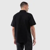Camisa de manga corta con cuello clásico, cierre frontal de botones y un bolsillo en el pecho. Presenta un diseño de corte regular con textura natural.