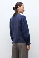 Remera de color blanco con cuello redondo y mangas largas abullonadas que presentan puños con volados.