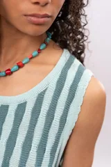 Vestido tejido a rayas verticales en tonos celeste y gris, sin mangas, con cuello redondo y corte recto. Incluye cinturón tejido con flecos.