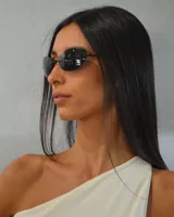 Anteojos de sol negros con lentes ovaladas y montura metálica fina.