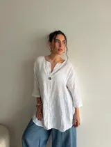 Blusa de viscosa con estampado de lunares, corte holgado, mangas tres cuartos y escote en V con botón central.