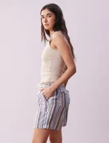 Short color crema con finas rayas verticales grises, pretina elastizada con cordón de ajuste, bolsillos delanteros y traseros.
