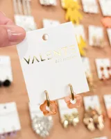 Aros colgantes con aro dorado y dije de acrílico con forma de flor color salmón.