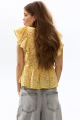 Top de algodón amarillo con estampado floreado, escote corazón, volados en los hombros y detalle de peplum en la cintura.