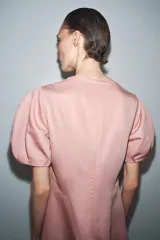 Vestido midi de cuello redondo y manga corta abullonada con terminación elástica. Presenta un diseño de corte evasé con cierre posterior de cremallera oculta.