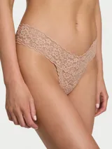 Tanga de encaje color beige con diseño floral, tiro bajo y ribetes festoneados.