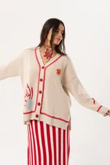Saco oversize tejido con ilustraciones inspiradas en corales, peces, estrellas de mar y tortugas. Presenta galón picot en rojo en cartera y puños, y botones a tono.
