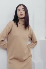 Vestido corto de tejido de punto en color beige, con cuello alto y mangas largas. Presenta puños y ruedo acanalados, con un diseño de calce relajado.