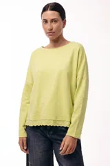 Remera de algodón color verde lima, de corte holgado y manga larga, con detalle de puntilla bordada en el ruedo.