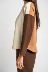 Sweater de algodón con diseño bicolor, cuerpo en color crema y mangas largas en color marrón oscuro. Presenta cuello redondo y un corte holgado tipo oversize.