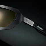Lentes de sol envolventes con montura de acero inoxidable en color gunmetal y lentes de nylon amarillos. Presentan un diseño deportivo con aberturas decorativas en la parte superior del marco y patillas de acetato.