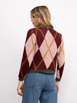 Cardigan de punto con patrón argyle en tonos azul marino, celeste y naranja. Presenta cuello redondo, cierre frontal con botones dorados y terminaciones en tejido acanalado gris.