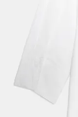 Camisa de algodón con cuello redondo y escote en pico, mangas tres cuartos con puños y bajo asimétrico redondeado.