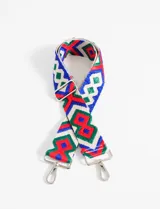 Correa de poliéster para cartera con diseño bordado de rombos en colores azul, rojo, verde y blanco. Tiene herrajes metálicos plateados y extremos de cuero sintético negro.
