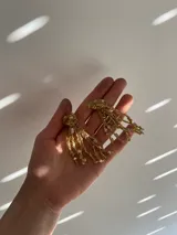 Aros colgantes hechos a mano con bronce, porcelana, piedras y otros materiales que le dan textura. Cada par es único e irregular.