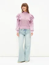 Buzo de tejido de punto calado en color lila, con cuello alto, mangas largas con puños ajustados y detalle de volados en los hombros.