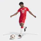 Camiseta de fútbol Adidas del FC Bayern, modelo local, color rojo con rayas verticales sutiles, detalles en blanco y dorado en el cuello y las mangas, y el logo del patrocinador en el pecho.