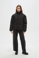 Campera puffer negra con cuello alto, cierre frontal oculto y puños tejidos acanalados. Diseño acolchado con bolsillos laterales.