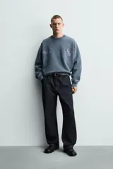 Sudadera de corte boxy fit con efecto lavado, cuello redondo y manga larga. Presenta estampados a contraste en color violeta en la parte frontal y acabados en rib en cuello, puños y ruedo.