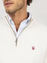 Sweater de punto acanalado en color azul marino, con cuello alto y cierre frontal parcial. Presenta mangas largas con puños acanalados y un pequeño logo bordado en rojo en el pecho.