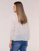Blusa confeccionada en gasa semitransparente con sutil acabado plisado y estampado floral en tonos suaves. Presenta cuello solapa redondeado, escote en V y botonadura frontal. Mangas largas con puños elásticos y ruedo anudado en la parte inferior frontal.