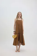 Vestido midi de lino color salmón, de corte amplio y silueta holgada. Presenta diseño con cortes irregulares y detalles de pasamanería en el escote y costuras. Cuenta con breteles dobles tipo cuerda y ruedo asimétrico.