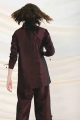 Vestido corto color borgoña, con capucha, cierre frontal y mangas largas fruncidas.