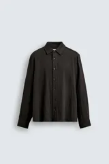 Camisa de corte relajado confeccionada en tejido fluido con mezcla de viscosa. Presenta cuello solapa, cierre frontal con botones y manga larga con puños abotonados.