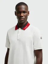 Polo de piqué de algodón color blanco, con cuello clásico a dos tonos (azul marino y rojo) y tapeta de dos botones.