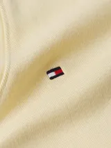 Remera de manga corta color amarillo pálido, con cuello en V y corte ajustado al cuerpo. Presenta un pequeño logo bordado de Tommy Hilfiger en el pecho.