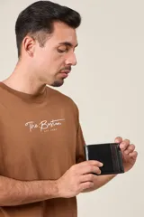 Billetera de cuero negro con franja decorativa marrón en el lateral. Diseño clásico con múltiples compartimentos para tarjetas y billetes.