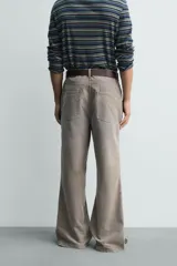 Pantalón de pana de corte flare, color verde oliva desgastado, con cinco bolsillos y cierre frontal de cremallera y botón.