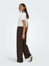 Pantalón suelto color marrón con estampado de lunares blancos, tiro medio y cintura elástica con cordón de ajuste.