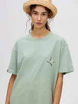 Remera verde agua con cuello redondo y manga corta, con un pequeño estampado de una estrella en el pecho. Corte holgado y cuadrado.