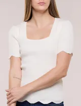 Blusa de punto acanalado color blanco, con escote cuadrado, mangas cortas y terminaciones festonadas en mangas y ruedo.