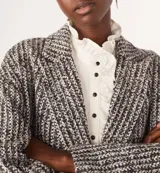 Tapado largo de tejido de punto con diseño de espiga en tonos blanco, negro y gris. Tiene cuello con solapas, doble botonadura y bolsillos laterales.